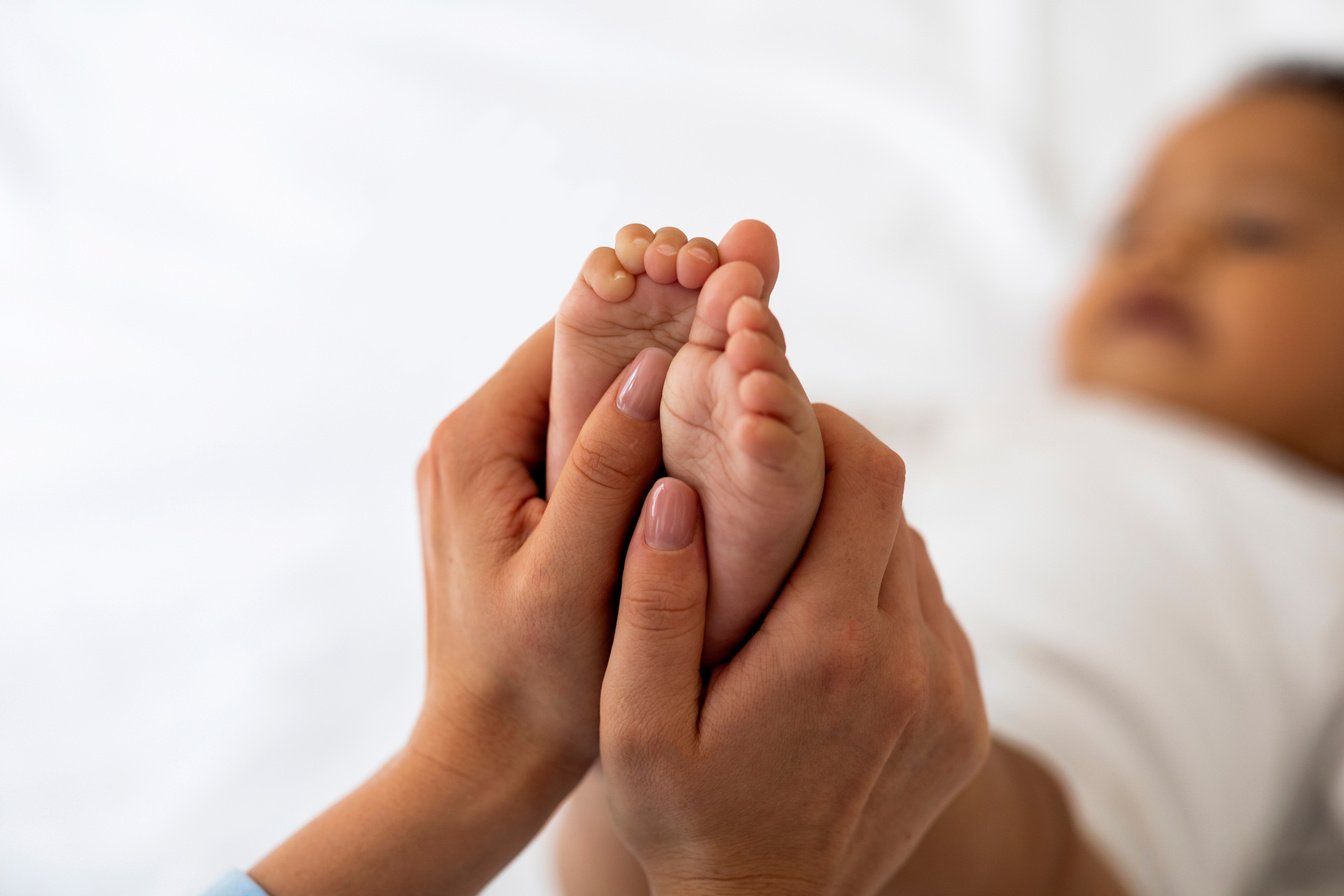 Baby Reflexology. Mother Massaging Tiny Feet Of Her Black Infant Child